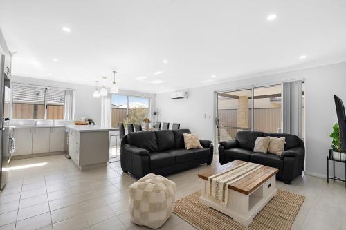 a living room with two couches and a kitchen at Spacious 4 Bedroom house in Southern River in Perth