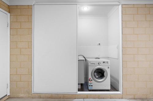 a washer and dryer in a room with white cabinets at Spacious 4 Bedroom house in Southern River in Perth