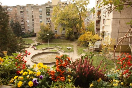 a garden with flowers and a fountain in a city at Apartment Spacious Liman in Novi Sad