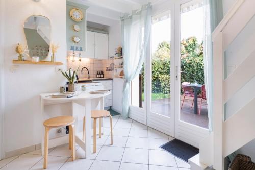 une cuisine avec une table et des tabourets dans une pièce dans l'établissement Maisonnette conviviale Piscine Activités pour Tous, à Guérande