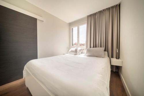 un lit blanc dans une chambre avec une fenêtre dans l'établissement Stardust Comédie - Élégant Confort & Terrasse, à Montpellier