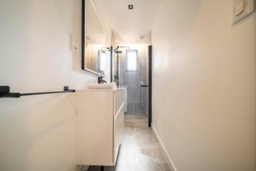 une salle de bain blanche avec un lavabo et un miroir dans l'établissement Stardust Comédie - Élégant Confort & Terrasse, à Montpellier