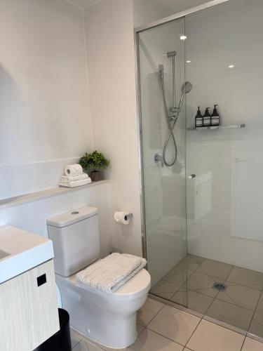 a white bathroom with a shower and a toilet at Luxury Stay With City View - Free Parking,Pool,Wifi in Brisbane