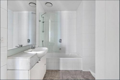 a white bathroom with a sink and a bath tub at Ultimate Southbank Getaway with Free Parking in Melbourne