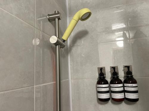 a shower with a yellow shower head next to two bottles at JAJA Haenggung, SuwonㅣNext to Hwaseong FortressㅣCozy Korean VibeㅣComfortable & Well-keptㅣUp to 8 guestsㅣFree Parkingㅣ2-night minimumㅣLoved by many guests in Suwon