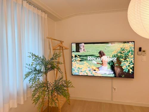 a flat screen tv hanging on a wall in a living room at JAJA Haenggung, SuwonㅣNext to Hwaseong FortressㅣCozy Korean VibeㅣComfortable & Well-keptㅣUp to 8 guestsㅣFree Parkingㅣ2-night minimumㅣLoved by many guests in Suwon