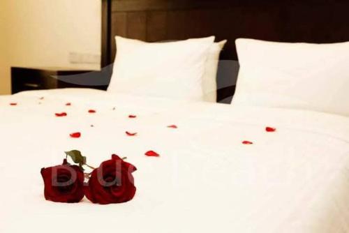 a white bed with two red roses on it at Blue Beach Hotel in Wadduwa