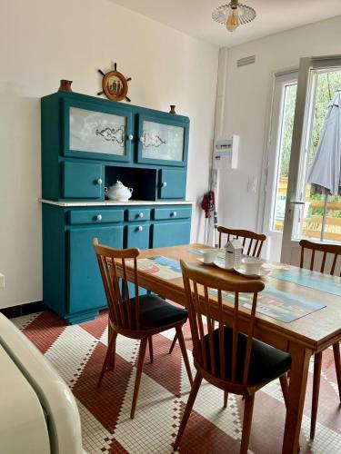 une salle à manger avec une table et un meuble bleu dans l'établissement Appartement avec jardin et SPA proche centre-ville et plage, au Château-dʼOléron