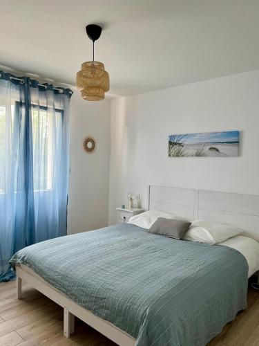 - une chambre blanche avec un lit et une couverture bleue dans l'établissement Appartement avec jardin et SPA proche centre-ville et plage, au Château-dʼOléron