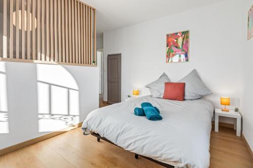 a bedroom with a bed with two blue pillows on it at Charming T4 - Cosy Air Conditioning in Béziers