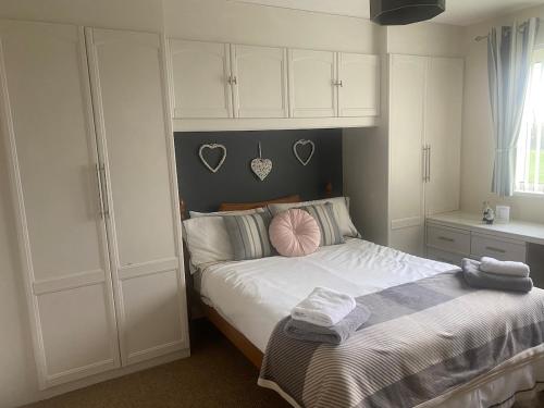 a bedroom with a bed and white cabinets at Fairways View at Haverfordwest Golf Club in Haverfordwest