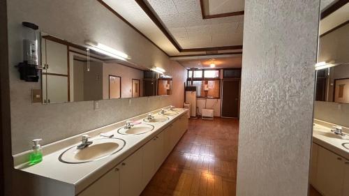 a bathroom with three sinks and a large mirror at Slopeside Lodge Hakuba in Otari