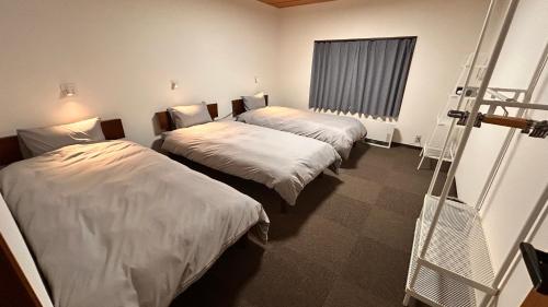 a room with two beds and a ladder in it at Slopeside Lodge Hakuba in Otari