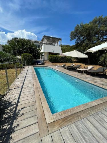 une piscine avec une terrasse en bois et une maison dans l'établissement ruscana, à Pinarellu