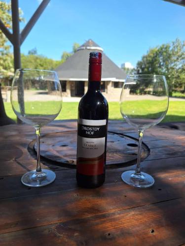 a bottle of wine and two glasses on a wooden table at Escape to Tranquility ! in Kiserian