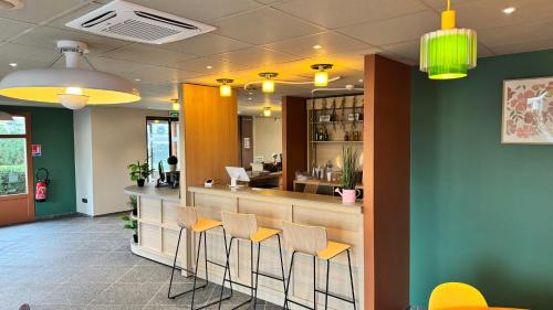 un bar dans un restaurant avec tabourets jaunes dans l'établissement B&B HOTEL Saint-Witz Roissy, à Saint-Witz