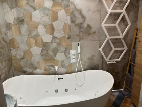 a bathroom with a white tub in a room at Wood & Stone Apartment in Gdańsk