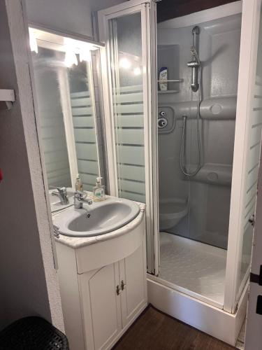une salle de bain blanche avec un lavabo et une douche dans l'établissement Les margouillats - maisonnette à 2 pas de la plage, à Vias