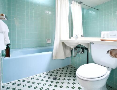 a bathroom with a toilet and a sink and a tub at Sunrise Hotel Okinawa-どこか懐かしいレトロな雰囲気の宿 in Okinawa City