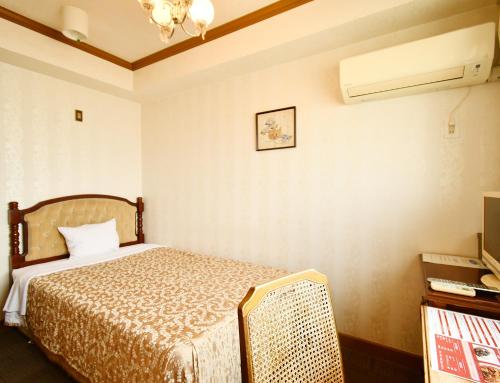 a hotel room with a bed and a television at Sunrise Hotel Okinawa-どこか懐かしいレトロな雰囲気の宿 in Okinawa City