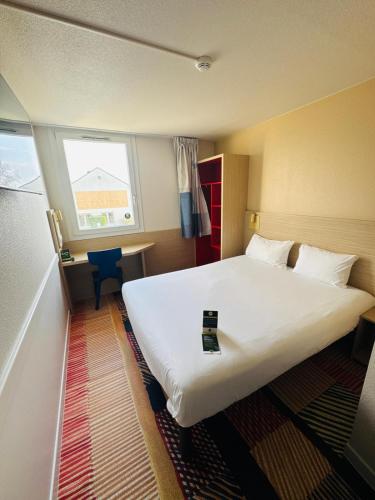 une chambre d'hôtel avec un grand lit et un bureau dans l'établissement B&B HOTEL Saint-Witz Roissy, à Saint-Witz