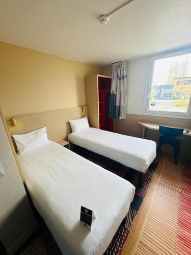 une chambre d'hôtel avec deux lits et une fenêtre dans l'établissement B&B HOTEL Saint-Witz Roissy, à Saint-Witz