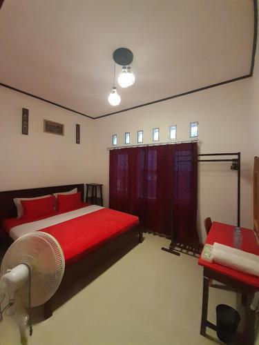 a bedroom with a red bed and a fan at The Sanduk Homestay in Rantepao
