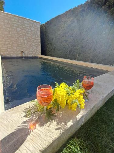 deux verres à vin et des fleurs sur une table à côté d'une piscine dans l'établissement La maison de Manon, 4-5personnes, 75m2, centre village avec piscine privée, à Maussane-les-Alpilles