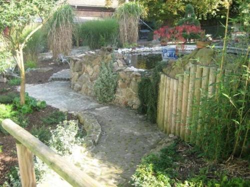 a garden with a stone fence and a pond at Ferienwohnung Uschkereit in Waldmünchen