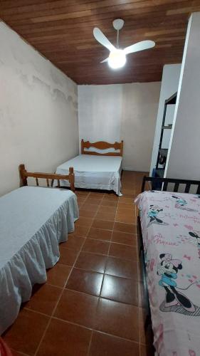 卡拉瓜塔图巴Casa com Piscina em Caraguatatuba的一间带两张床和吊扇的卧室
