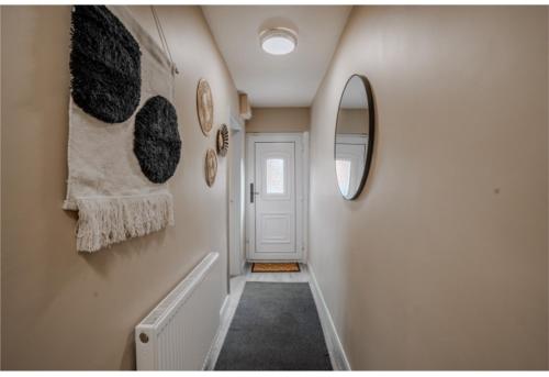 un couloir avec une porte blanche et un miroir dans l'établissement Jasmine Cottage, à Skipsea