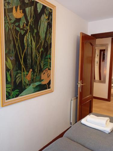 a painting hanging on a wall next to a bed at Calderón Playa in Gijón