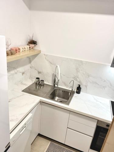 a kitchen with a sink and white marble walls at Capital Apartment Tirana in Tirana