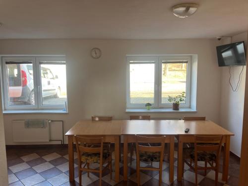 a dining room with a wooden table and two windows at Ubytování Sedmička in Dolní Rožínka
