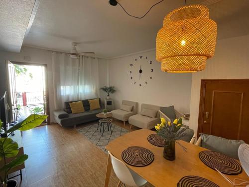 a living room with a table and a couch and a clock at Oasis en la playa con piscina in San Pedro del Pinatar