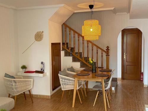 a dining room with a table and chairs and a staircase at Oasis en la playa con piscina in San Pedro del Pinatar