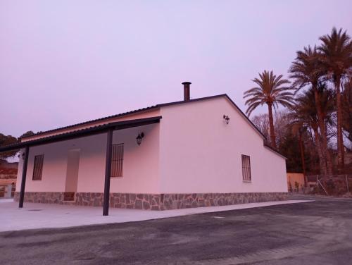 a white building with palm trees in the background at La Olmeda del Maripinar in Cieza
