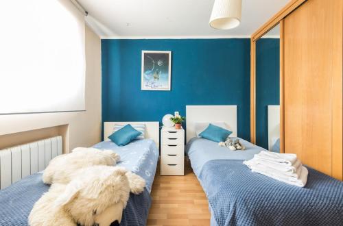 two beds in a room with blue walls at The Escorial House in Escorial