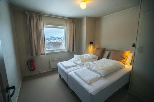 a bedroom with a bed with white sheets and a window at Sommarøy Apartment 2nd floor in Sommarøy
