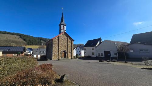 a small church with a steeple on a street at RINGZEIT-Lodge in Herresbach