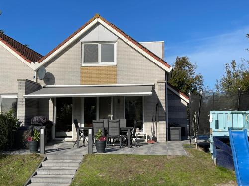 a house with a patio with a table and chairs at familienfreundliches Ferienhaus mit Ruderboot, Sauna und Kamin sowie E-Ladestation in Makkum