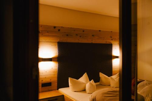 a bedroom with a bed with white pillows and a mirror at Hotel Klockerhof in Lermoos