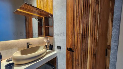 ein Badezimmer mit Waschbecken und Holztür in der Unterkunft Coconut Lane's Secret Villa, Secluded, Spacious, Hi-tech, 2-floor, Priv Garden & Saltwater Pool in Ko Phangan