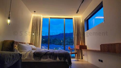 ein Schlafzimmer mit einem Bett und einem großen Fenster in der Unterkunft Coconut Lane's Secret Villa, Secluded, Spacious, Hi-tech, 2-floor, Priv Garden & Saltwater Pool in Ko Phangan