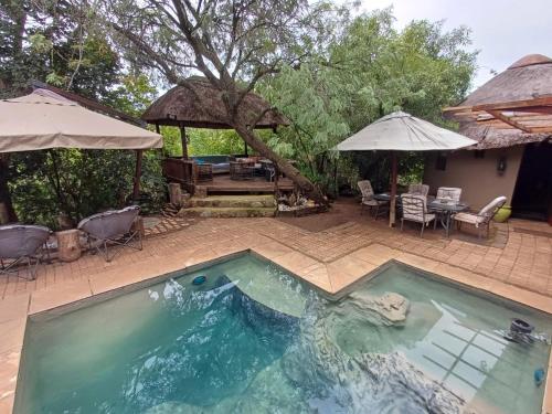 a swimming pool with a table and chairs and an umbrella at Rustic Unique - Bush Glamping Retreat in Kalkheuvel