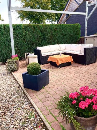 a patio with a white couch and a table and flowers at Landhausidyll 2 in Grundshagen