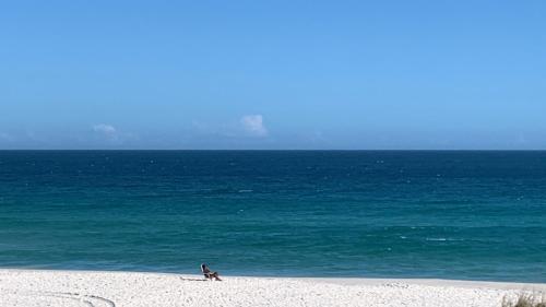 a person sitting on the beach near the ocean at Iris Pousada Hostel Arraial do Cabo in Arraial do Cabo