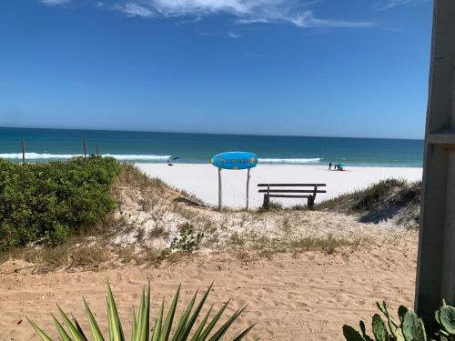 a picnic table on the beach with the ocean in the background at Iris Pousada Hostel Arraial do Cabo in Arraial do Cabo