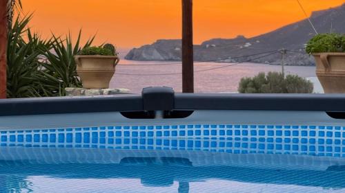 a swimming pool with a sunset in the background at Orionas in Tsoútsouros