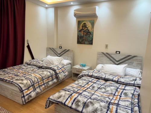 a bedroom with two beds and a painting on the wall at Rehab Modern Apartment in New cairo